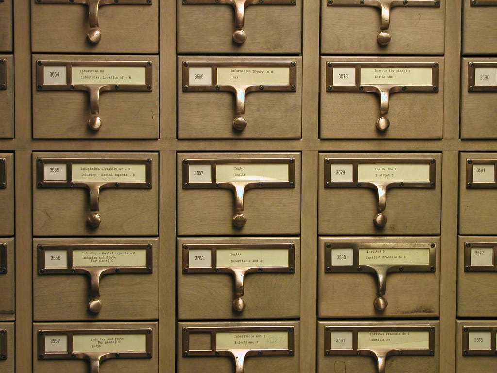 A wooden library card catalog with rows of small labeled drawers — an index that points you to the right note.
