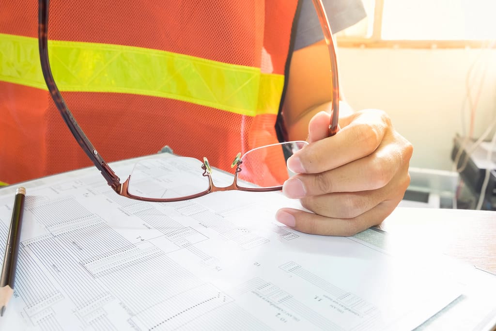 An engineer at a desk in morning light, drawing a fiber-optic core-assignment diagram by hand before any cable is run
